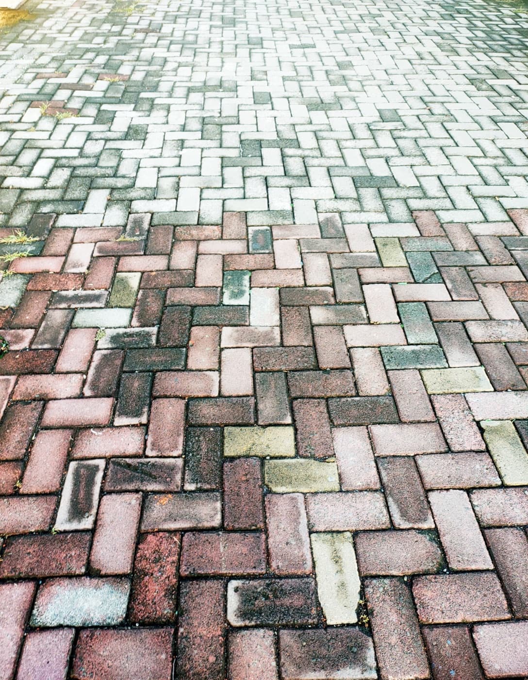 Paver intertravado em padrão herringbone com sinais de uso e desgaste