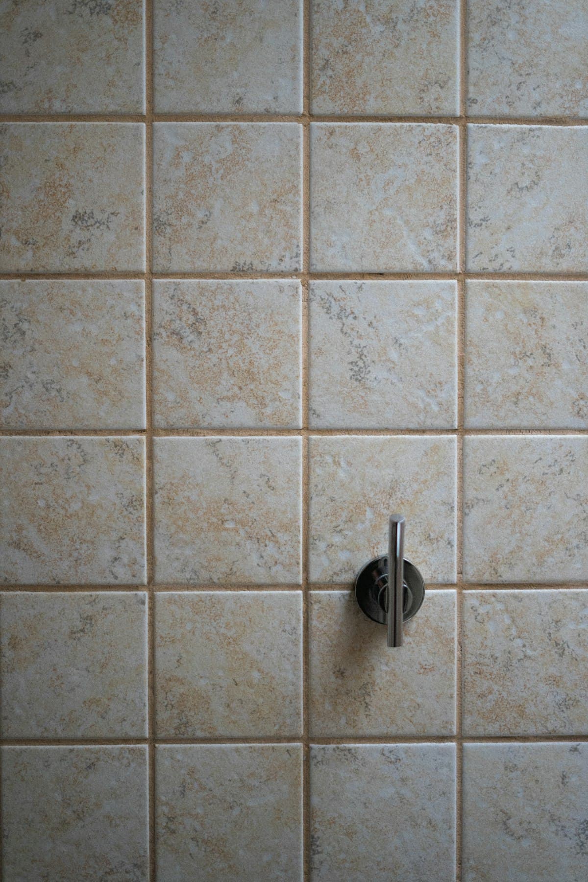 Parede de banheiro com azulejos cerâmicos e juntas de rejunte cinza